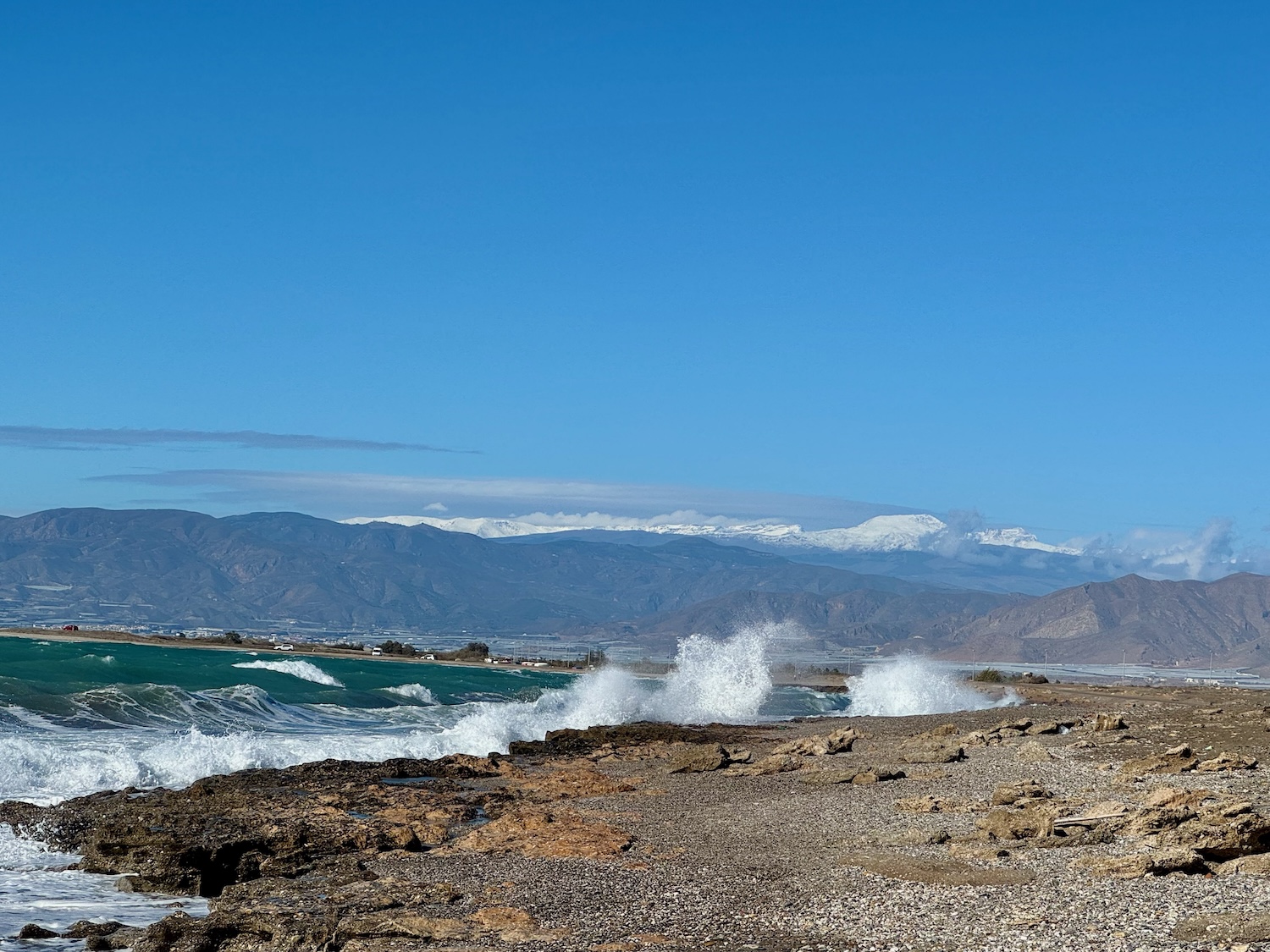 Spritzende Wellen, Strand und Schneeberge